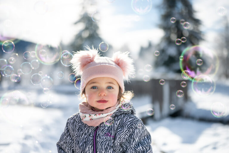 Séance photo famille dans le Haut-Jura : portrait d’une petite fille en bonnet dans la neige