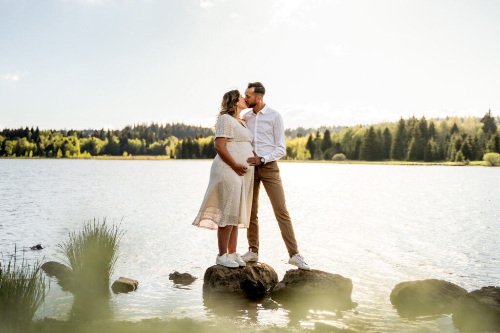Séance grossesse au lac de Bellefontaine – baiser du couple sur les rochers