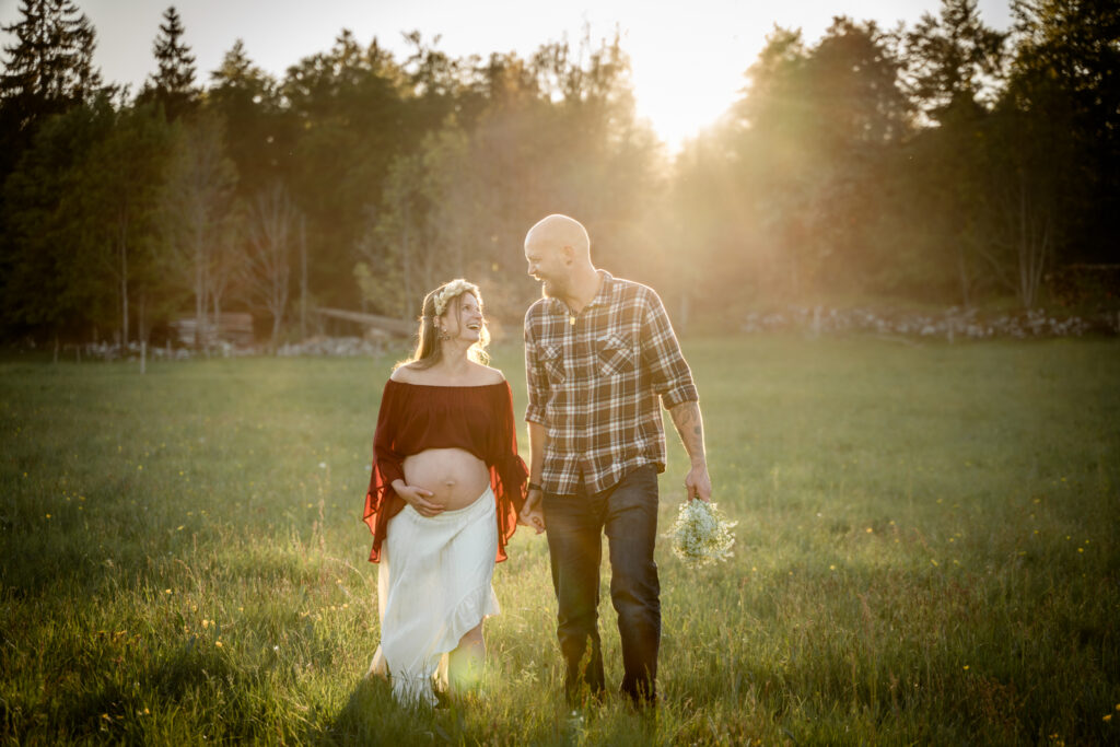 Photographe grossesse Jura – couple marchant dans un champ au coucher du soleil près de Morez
