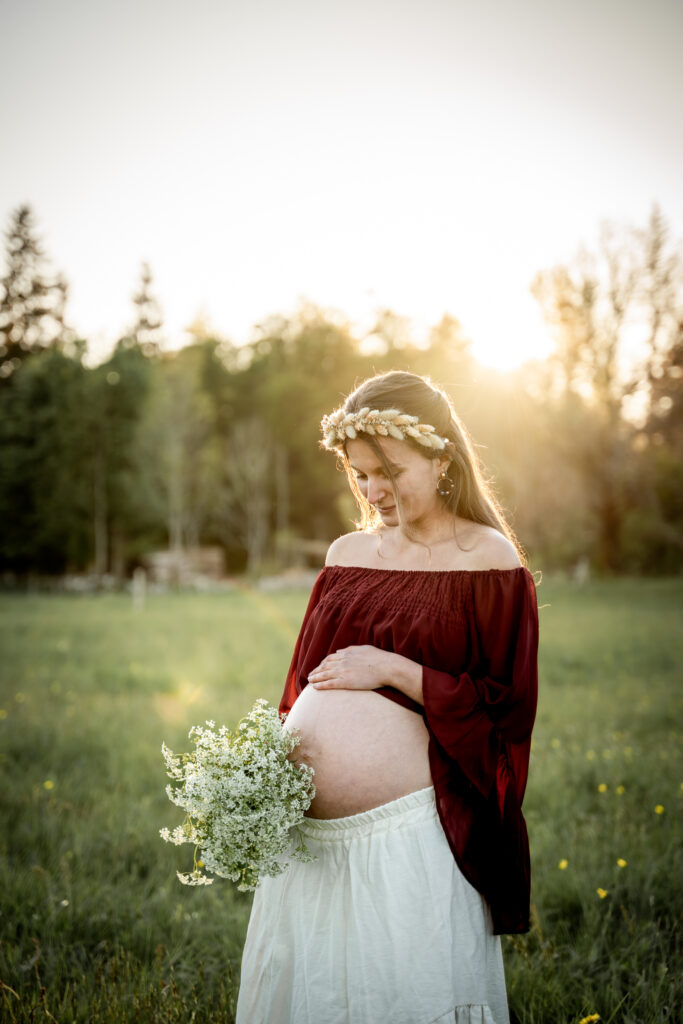 Photo de grossesse près de Morez – future maman avec couronne de fleurs à contre-jour