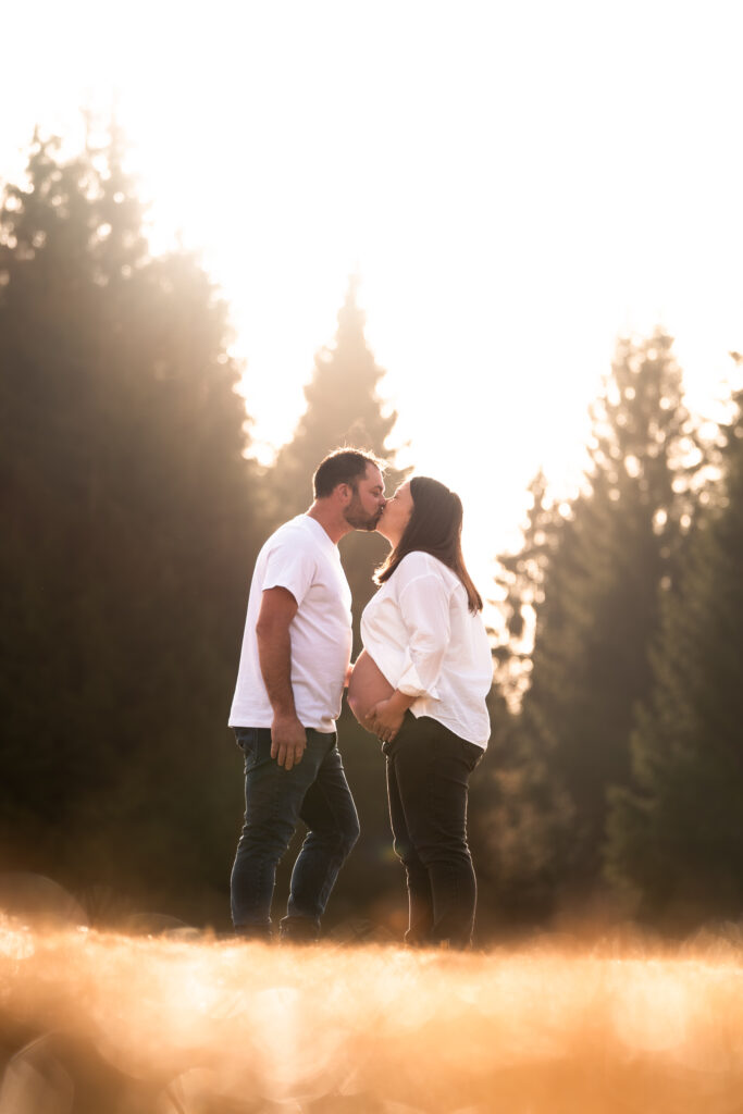 Photographe grossesse Jura – baiser à contre-jour dans un champ à Saint-Laurent-en-Grandvaux