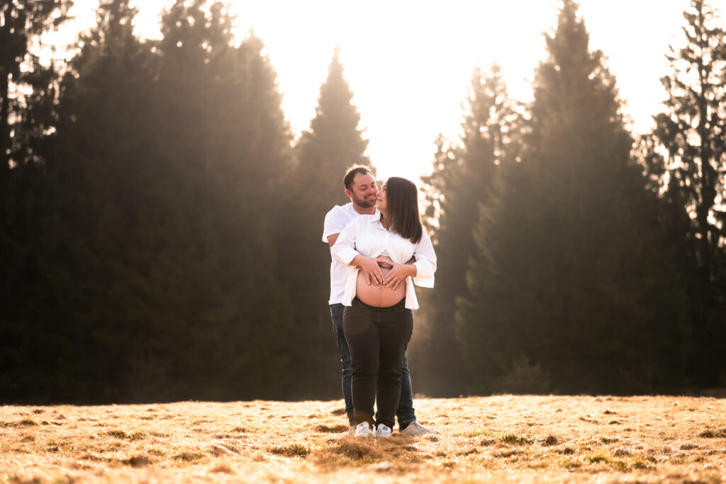 Photographe grossesse Jura – couple enlacé dans un champ à Saint-Laurent-en-Grandvaux