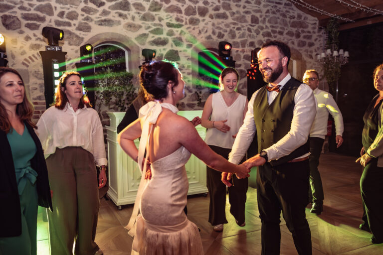 Photographe mariage Jura : mariée qui danse avec ses invités dans la salle en pierre