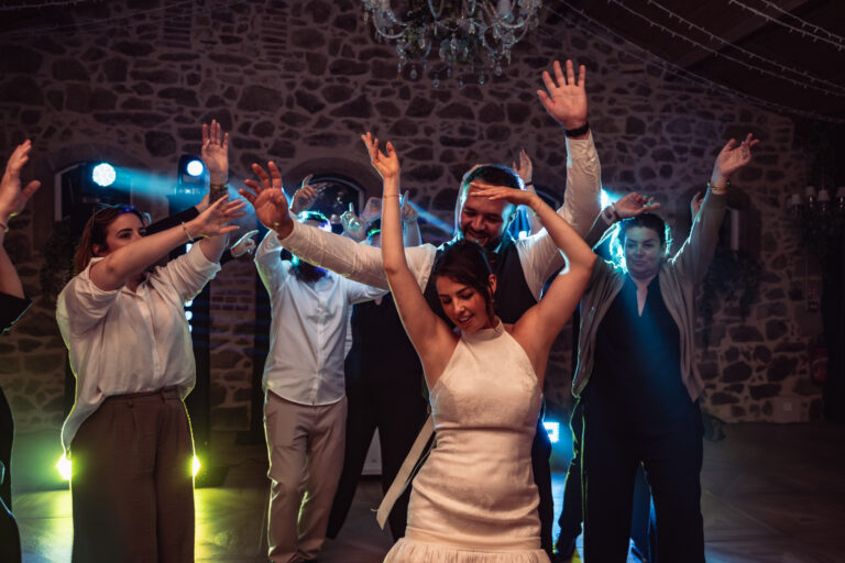 Photographe mariage Jura : mariés et invités qui dansent bras levés