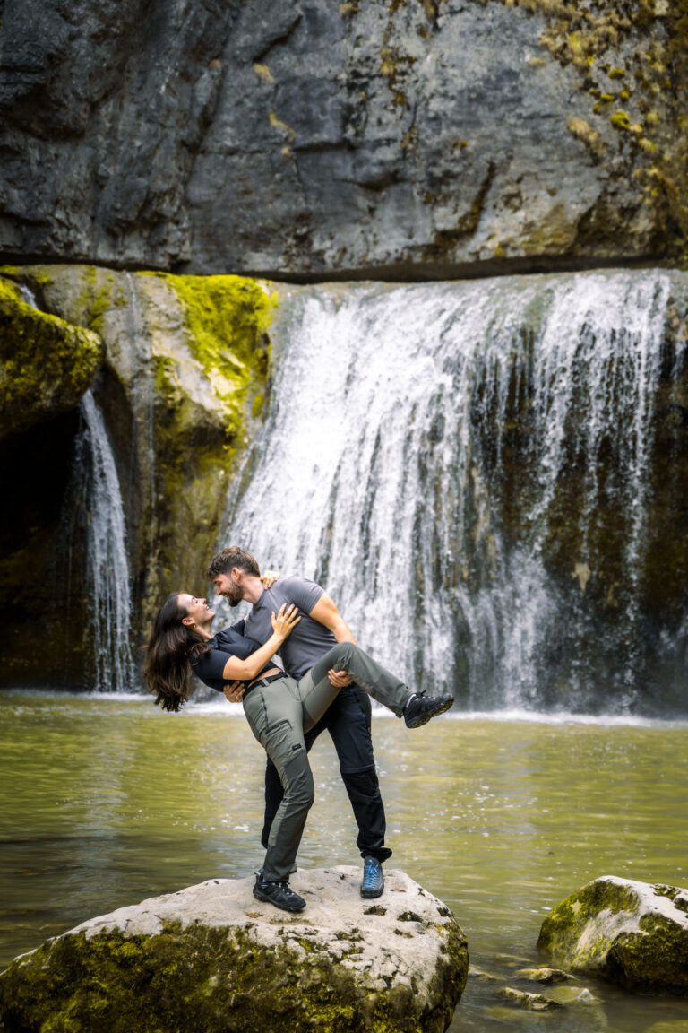Photographe mariage couple Morez Jura Genève Lausanne Champagnole Lons-le-Saunier Besançon – couple en éclats de rire sur un rocher au pied d’une cascade