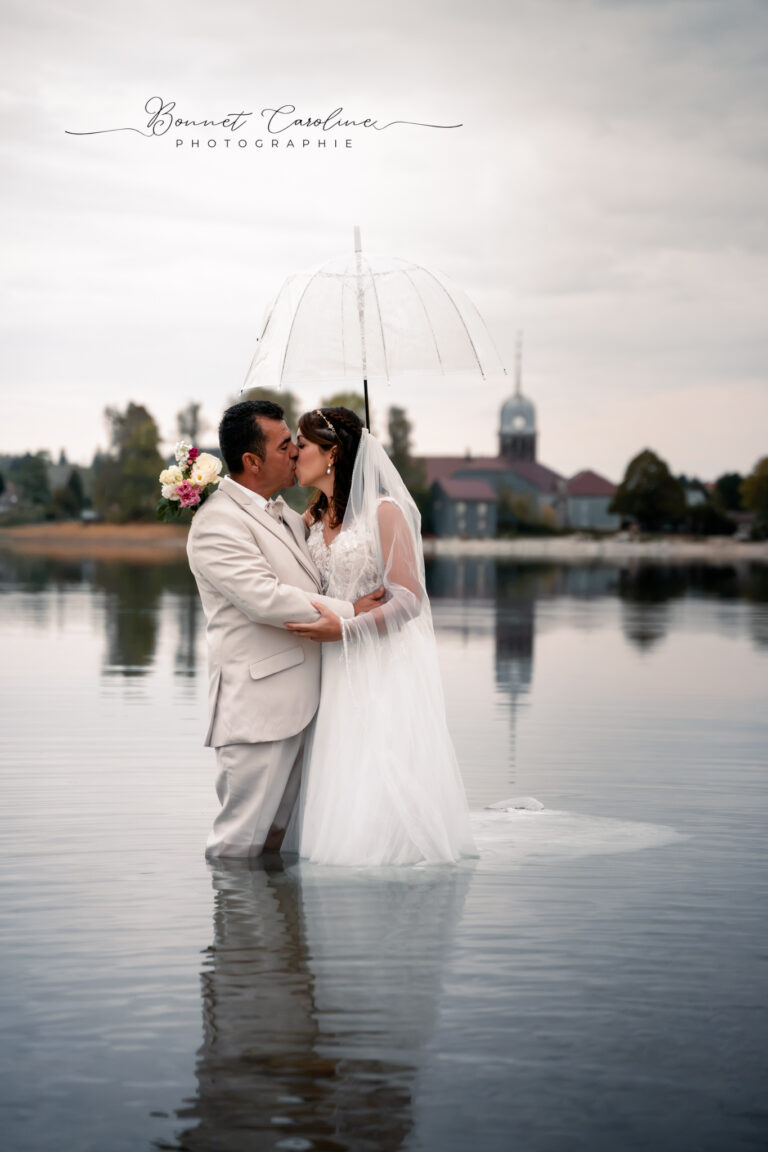 Photographe mariage Jura : mariés qui s’embrassent sous le voile, reflétés dans le lac