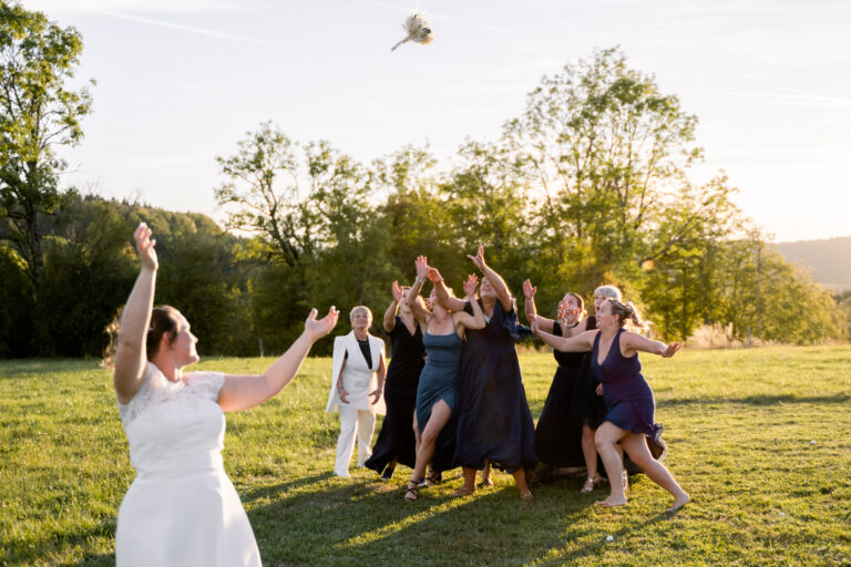 Photographe mariage Jura : mariée qui lance son bouquet aux invitées