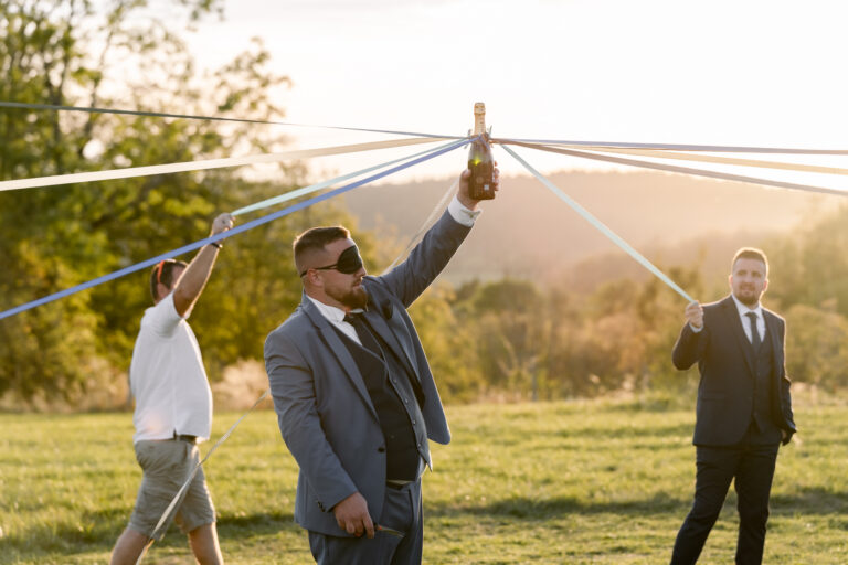 Photographe mariage Jura : invité qui joue avec un ruban dans un pré