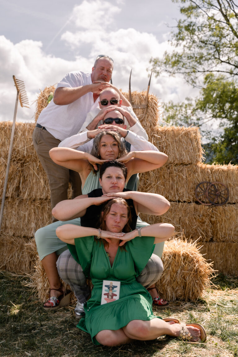 Photographe mariage Jura : pyramide d’amis complices sur les bottes de paille