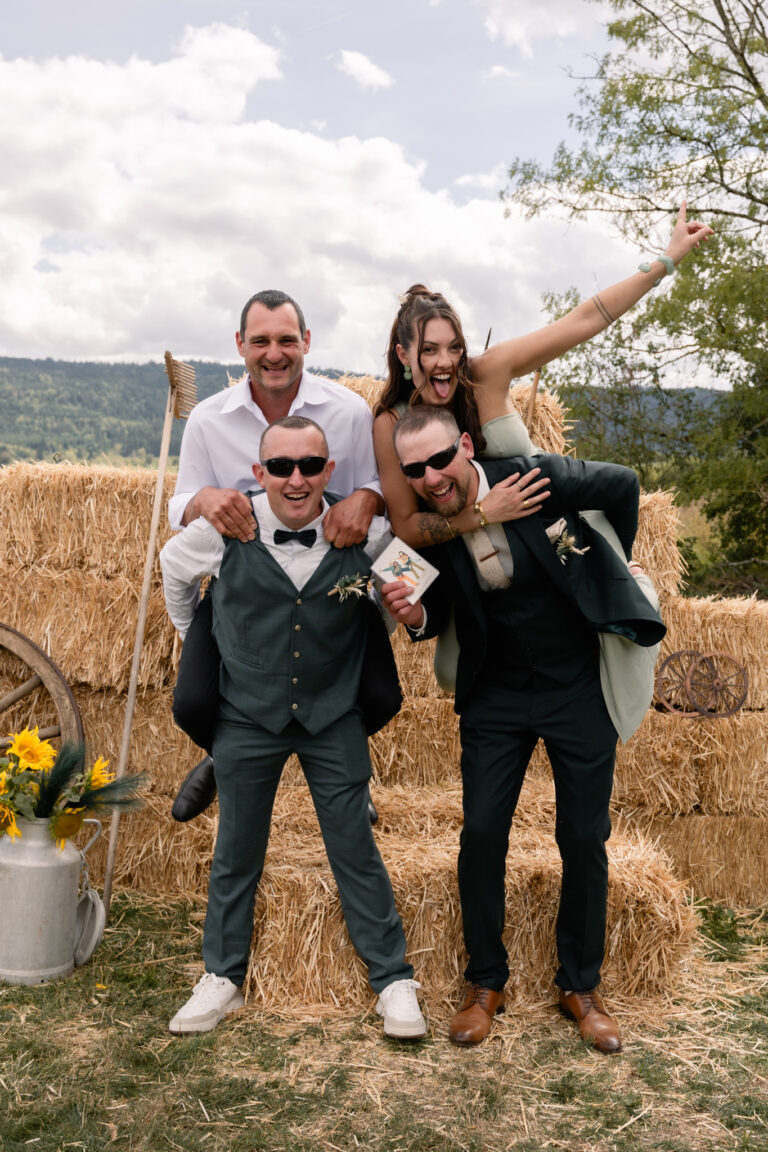 Photographe mariage Jura : marié et ses amis qui posent devant les bottes de paille