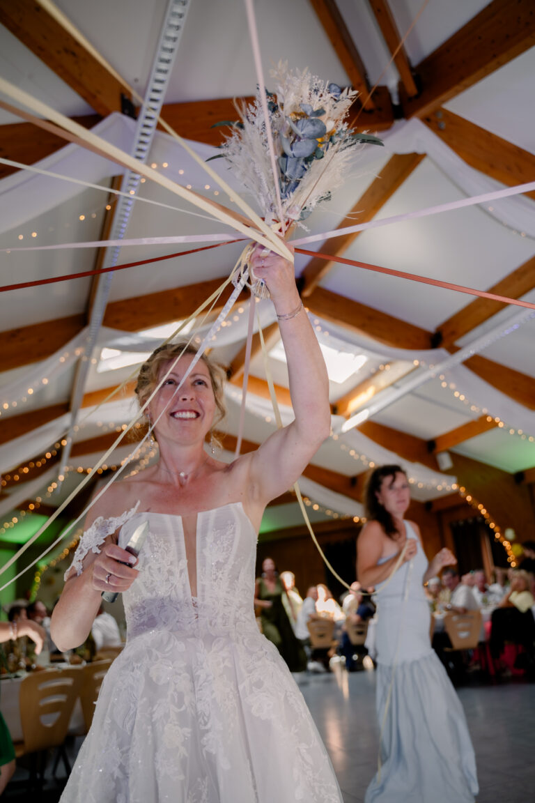 Photographe mariage Jura : mariée qui lève les bras sous les rubans