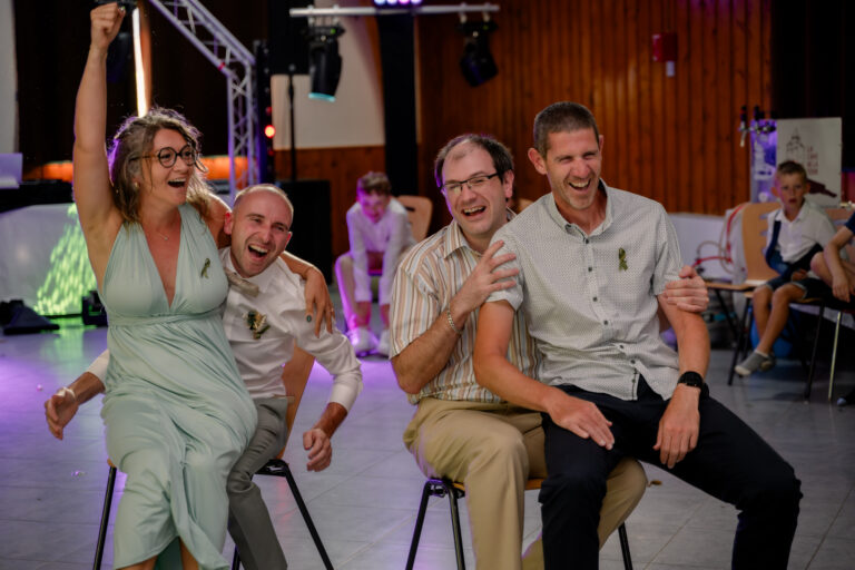 Photographe mariage Jura : invités qui rient aux éclats pendant un jeu