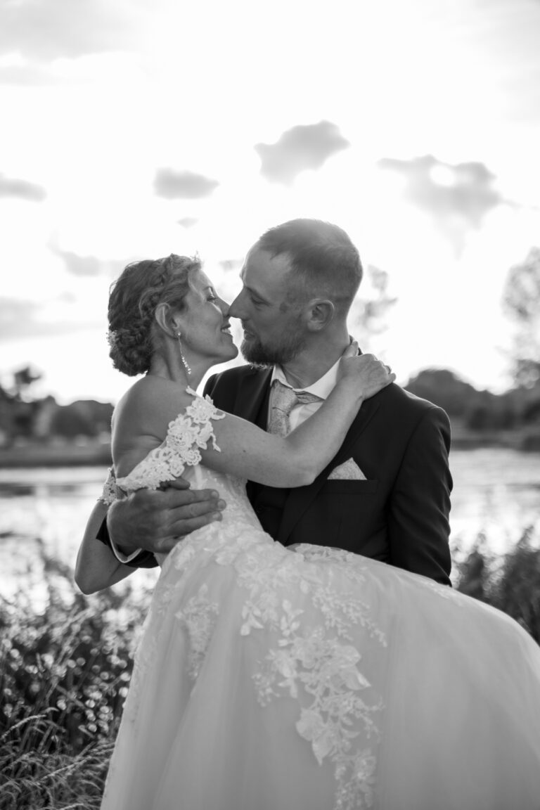 Photographe mariage Jura : mariés enlacés, robe de dentelle qui virevolte, en noir et blanc
