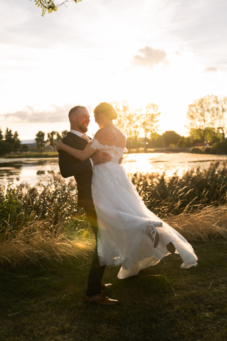 Photographe mariage Jura : mariés qui dansent au bord d’un étang à contre-jour