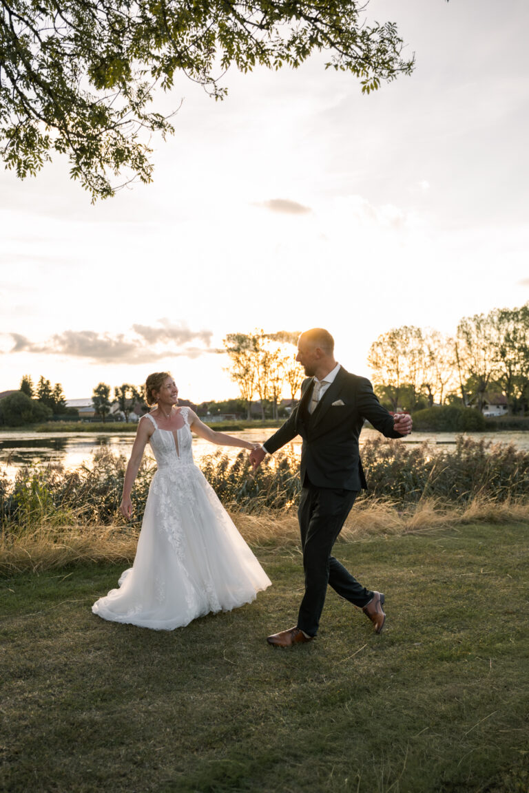 Photographe mariage Jura : mariés qui marchent main dans la main au bord d’un étang