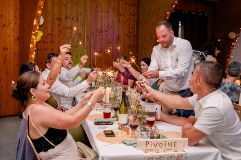 Photographe mariage Jura : invités qui applaudissent à table dans la salle en bois