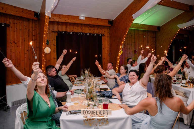 Photographe mariage Jura : invités qui lèvent les bras pendant le dîner