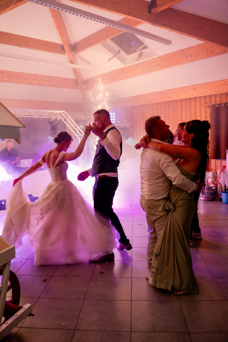 Photographe mariage Jura : mariés qui dansent avec leurs proches dans la fumée