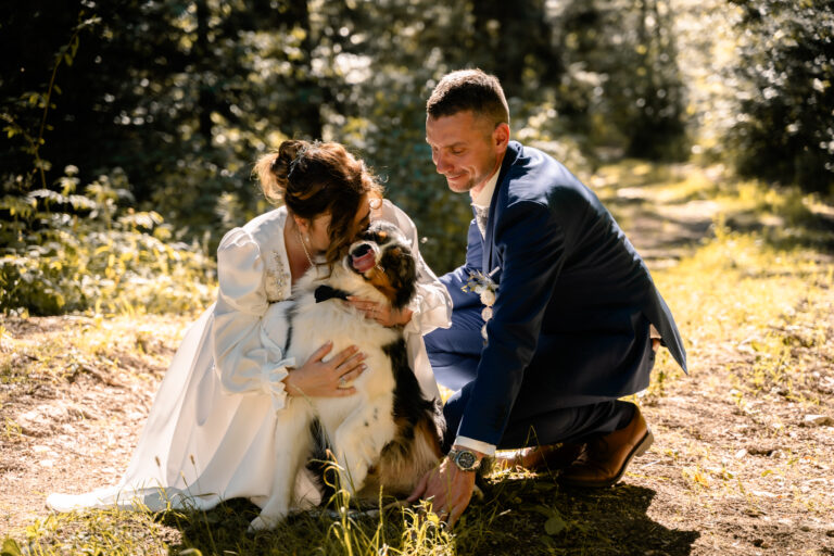 Photographe mariage Jura : mariés qui câlinent leur chien en lisière de forêt