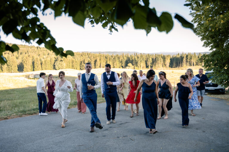 Photographe mariage Jura : invités qui dansent sur la route en plein air