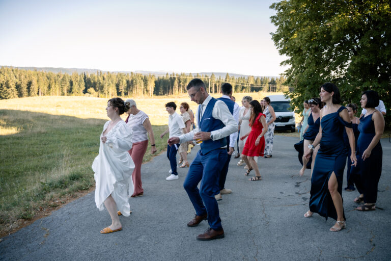 Photographe mariage Jura : mariés et invités qui dansent en ligne