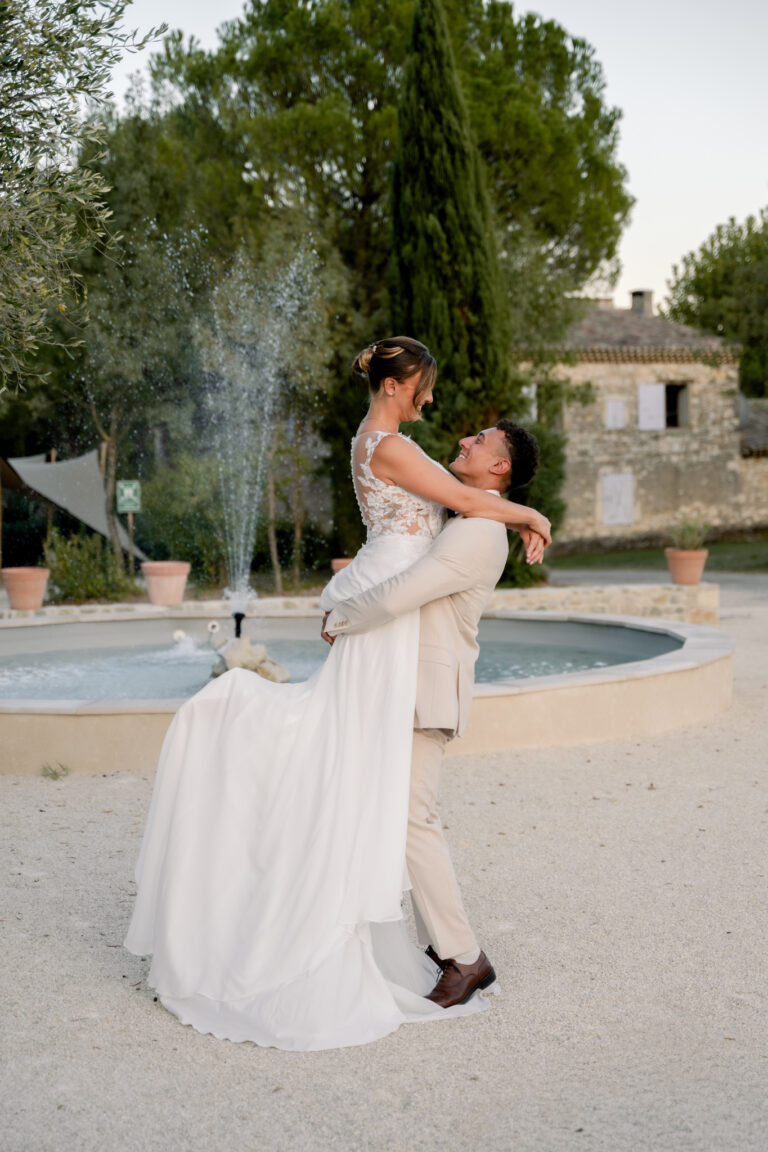 Photographe mariage Jura : marié qui porte sa mariée devant une fontaine