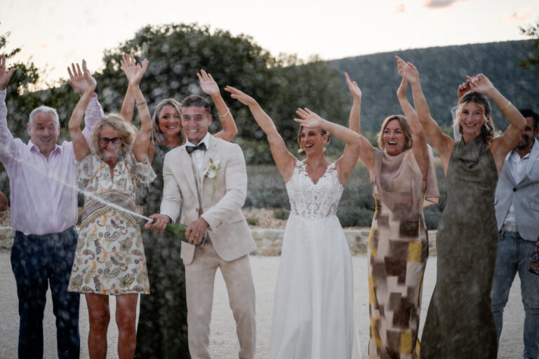 Photographe mariage Jura : invités qui lèvent les bras pour les mariés