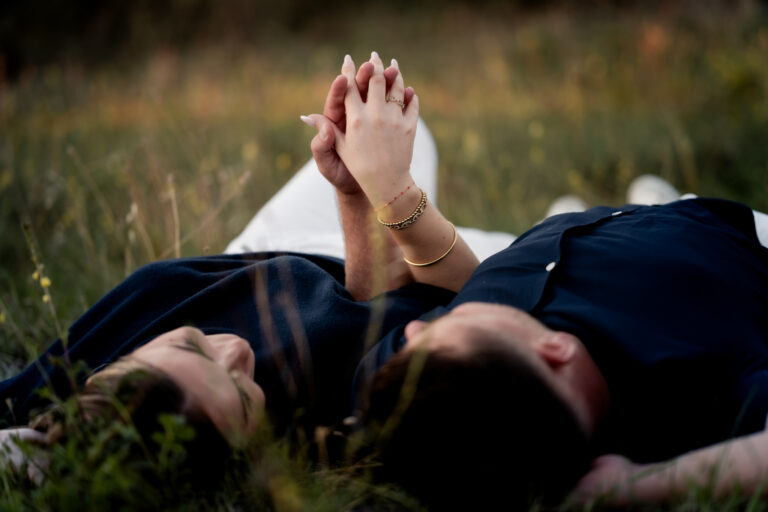 Photographe mariage couple Morez Jura Genève Lausanne Champagnole Lons-le-Saunier Besançon – couple allongé dans l’herbe, mains jointes