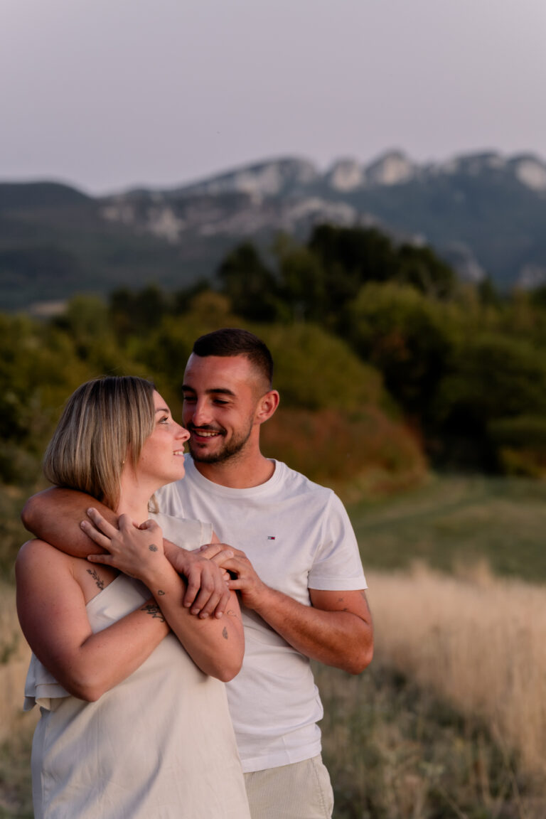 Photographe mariage couple Morez Jura Genève Lausanne Champagnole Lons-le-Saunier Besançon – couple souriant dans un pré face aux montagnes