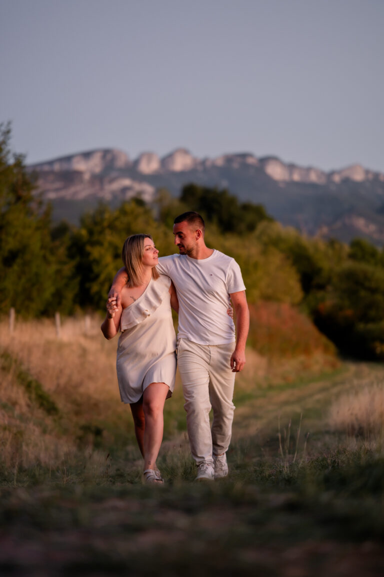 Photographe mariage couple Morez Jura Genève Lausanne Champagnole Lons-le-Saunier Besançon – couple marchant dans un pré face aux montagnes