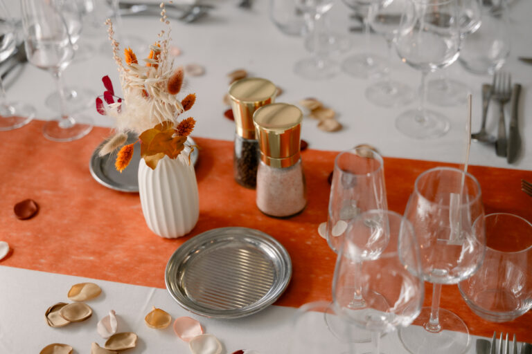 Photographe mariage Jura : table de mariage décorée d’un chemin de table orange et de fleurs séchées