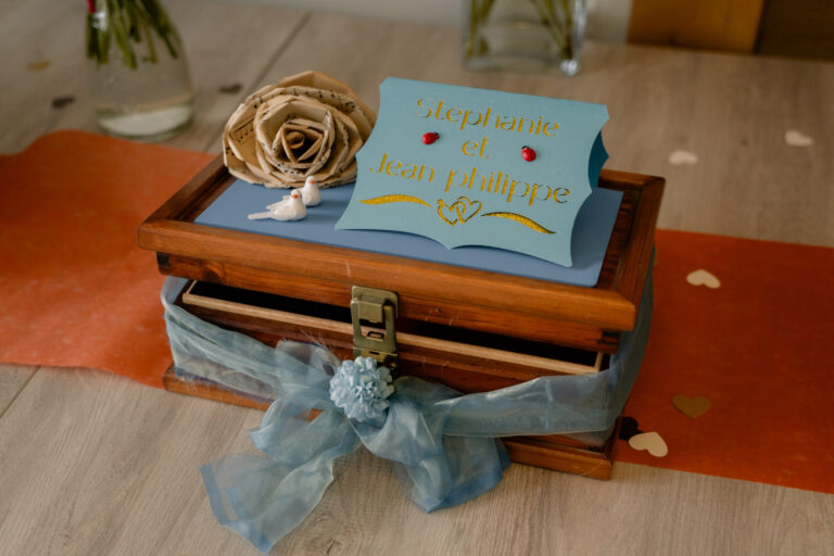 Photographe mariage Jura : urne en bois et ruban bleu sur la table des cadeaux