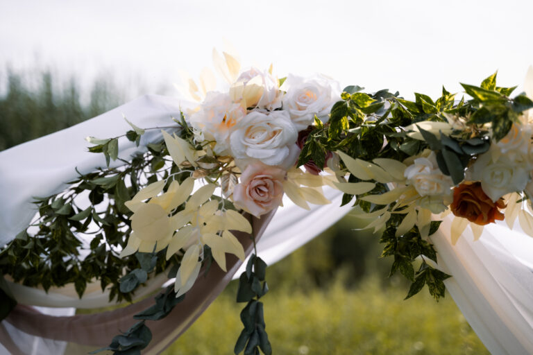 Photographe mariage Jura : détail de l’arche de cérémonie en fleurs blanches et feuillage