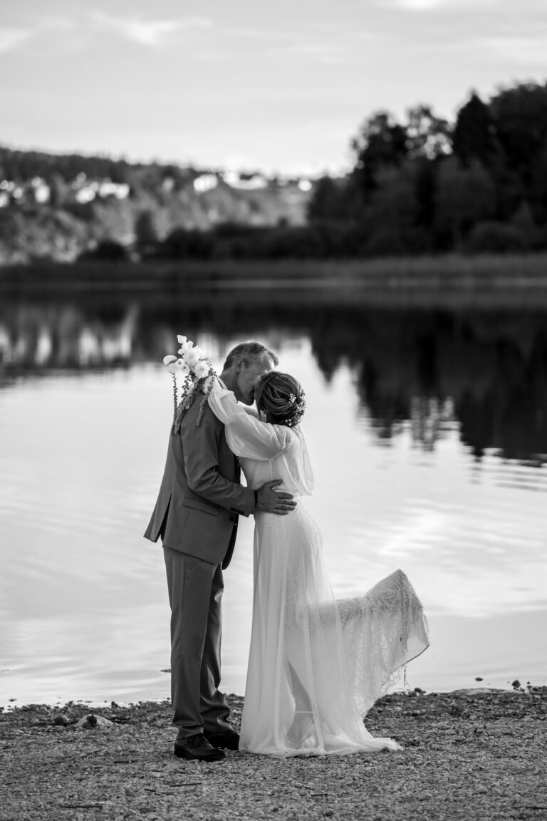 Photographe mariage Jura : mariés qui s’embrassent au bord du lac, en noir et blanc