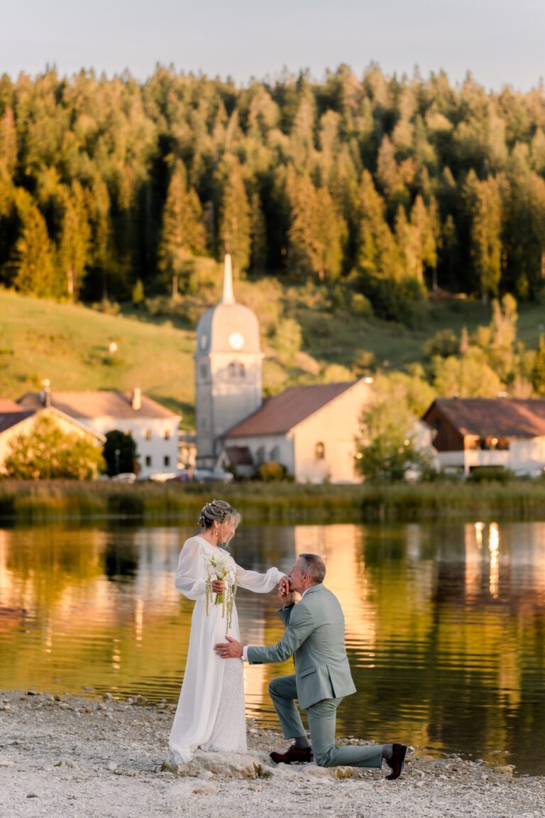 Photographe mariage Jura : marié à genoux devant sa mariée au bord du lac de l’Abbaye, dans le Jura