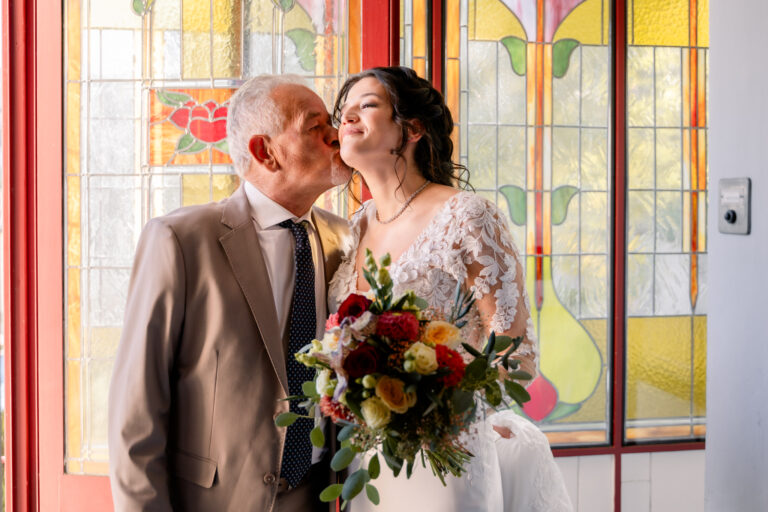Photographe mariage Jura : moment tendre entre la mariée et un proche devant les vitraux