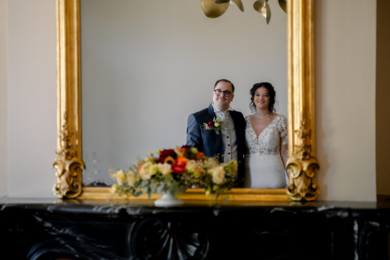 Photographe mariage Jura : mariés qui se reflètent dans un grand miroir doré