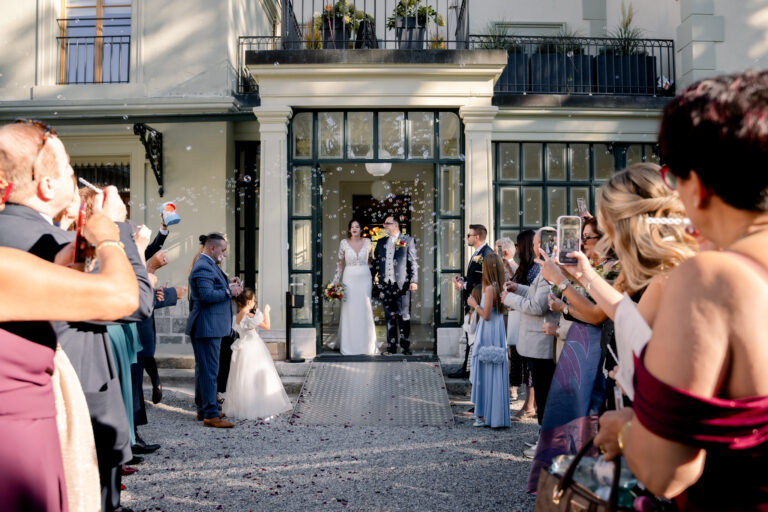 Photographe mariage Jura : invités qui filment la sortie des mariés du Château de Crissier