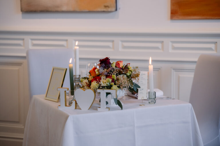 Photographe mariage Jura : table d’honneur aux bougies et bouquet de fleurs colorées