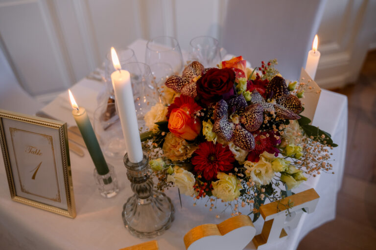 Photographe mariage Jura : bouquet de fleurs d’automne et bougies sur la table d’honneur