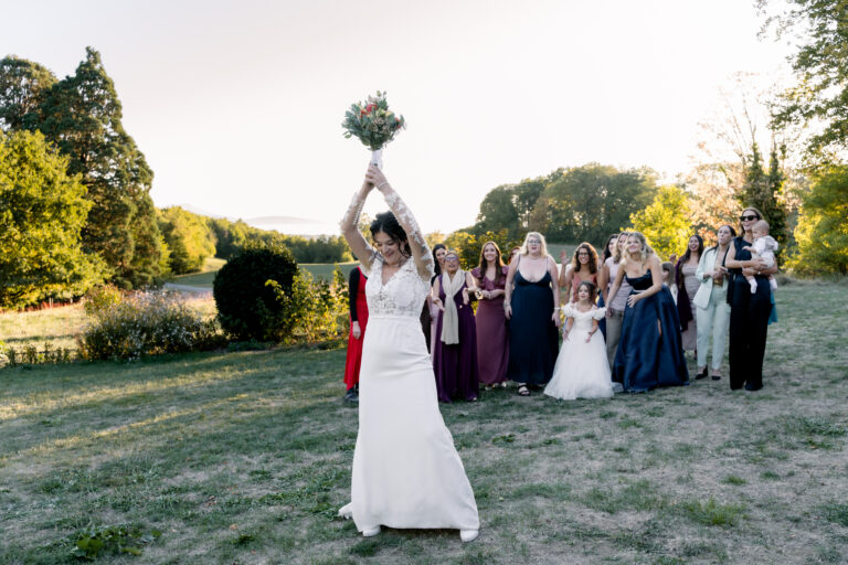 Photographe mariage Jura : mariée qui lance son bouquet dans le jardin