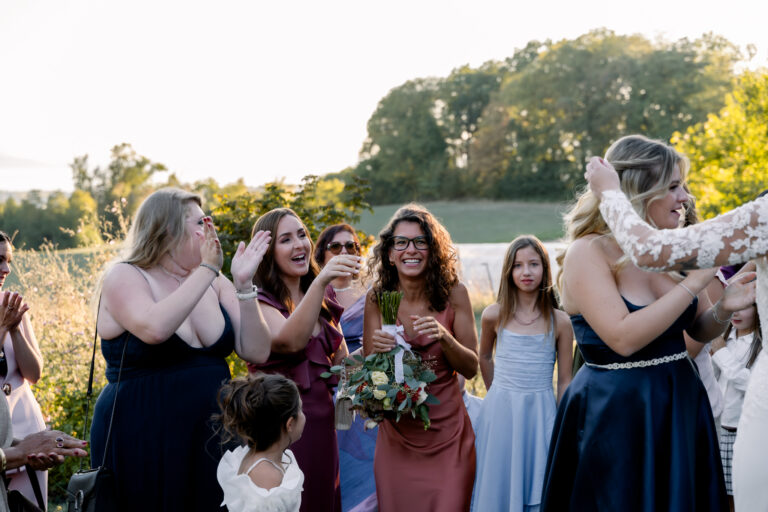 Photographe mariage Jura : invitées qui rient pendant le lancer de bouquet