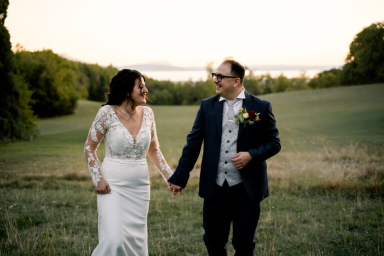 Photographe mariage Jura : mariés qui marchent dans un pré au bord du lac