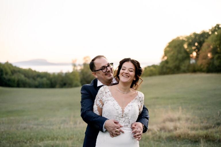 Photographe mariage Jura : mariés qui rient ensemble dans un pré au coucher du soleil