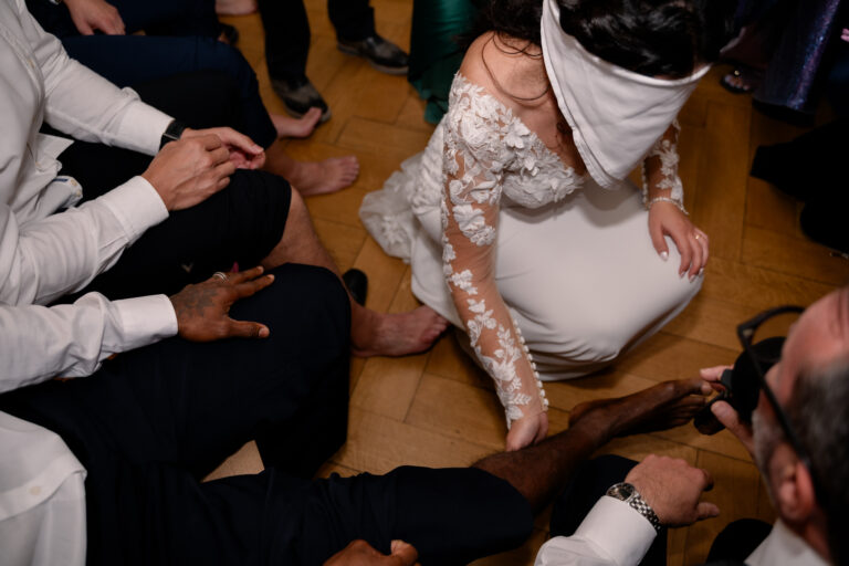 Photographe mariage Jura : mariée aux yeux bandés qui doit retrouver son marié en touchant les chevilles des invités