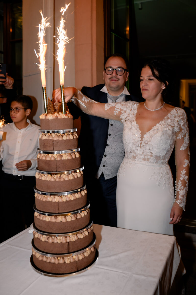 Photographe mariage Jura : mariés qui découvrent leur gâteau avec les cierges magiques