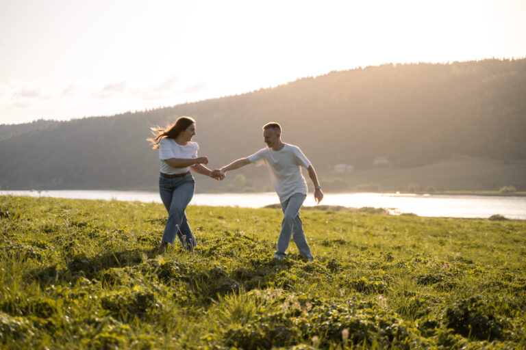 Photographe mariage couple Morez Jura Genève Lausanne Champagnole Lons-le-Saunier Besançon – couple dansant dans un pré au-dessus d’un lac