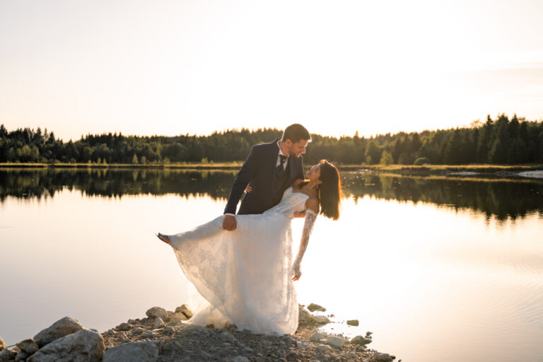Photographe mariage Jura : marié qui fait basculer sa mariée au bord du lac à contre-jour