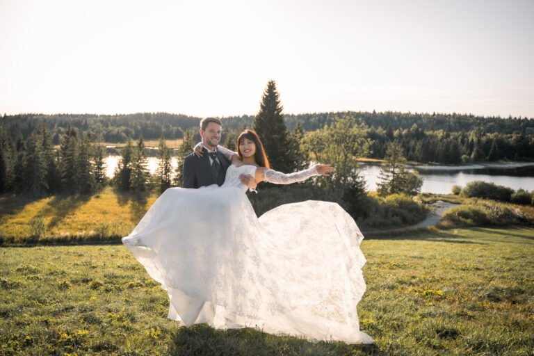 Photographe mariage Jura : marié qui fait tournoyer sa mariée au bord du lac de l’Abbaye