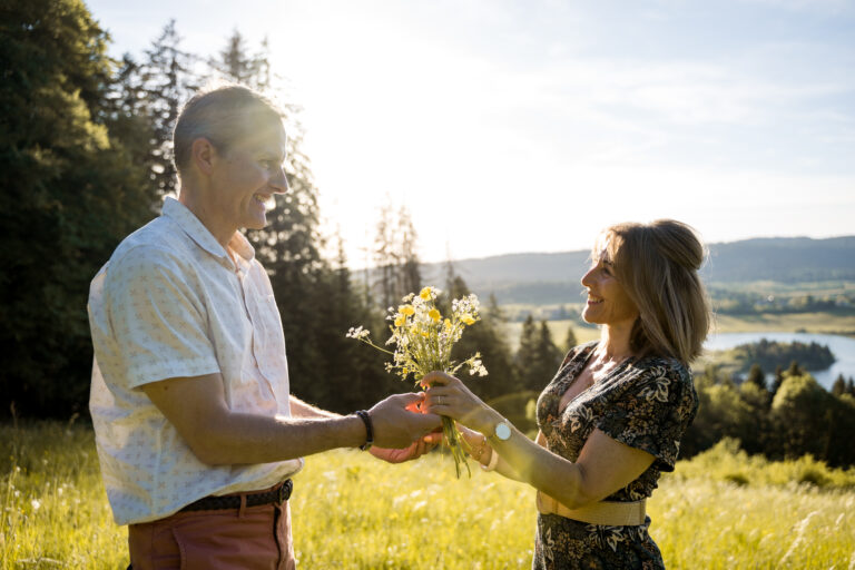 Photographe mariage couple Morez Jura Genève Lausanne Champagnole Lons-le-Saunier Besançon – couple au bord d’un lac, bouquet de fleurs à la main